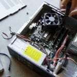 A Caucasian Man's Hands Use a Screwdriver to Dismantle a Computer Lying in Pieces of the Floor